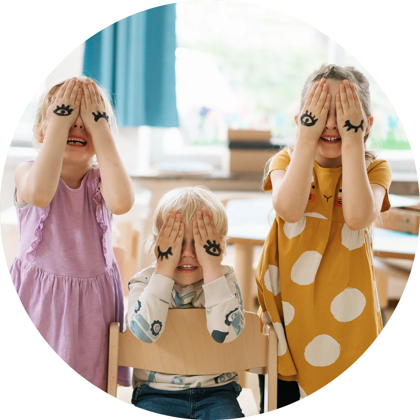 3 Kinder halten sich die Hände vor die Augen. Auf ihre Handrücken sind Augen gemalt, alle lachen